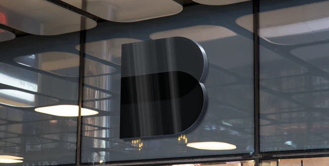 Modern 3D Baaark logo in glossy black mounted on reflective glass window with ambient office lighting